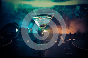 Glass with martini with olive inside on dj controller in night club. Dj Console with club drink at music party in nightclub with d