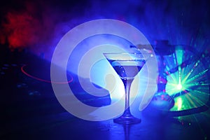 Glass with martini with olive inside on dj controller in night club. Dj Console with club drink at music party in nightclub with d