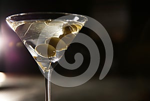 Glass of martini with olives in bar. Space for text