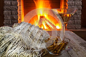 Glass of martini wine against cozy fireplace background, winter