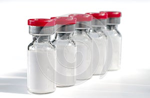 Glass medical vials of biotech drugs with red caps isolated on the white background. photo