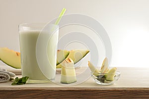 Glass with melon milk shake on wooden bench isolated background