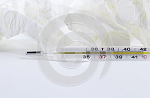 Glass mercury thermometer with celsius degree and napkins. Illness, high temperature concept. Thermometer close-up on white