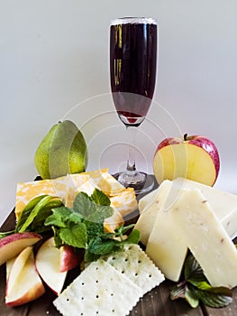 A glass of merlot with cheeses and fruit.