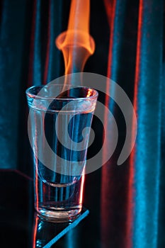 Glass of Mexican tequila, vodka with burning liquid. Glass of vodka on black with flames.