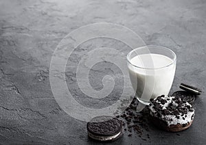 Glass of milk and black sandwich cookies with doughnut and ice cream on black stone kitchen table background. Space for text
