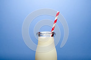 Glass of milk on blue background with straw