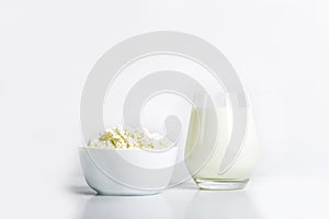 Glass of milk and bowl with homemade cottage cheese on a white background. The concept of healthy dairy products with calcium.
