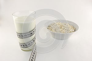 A glass of milk and a centimeter tape of oatmeal white background measure