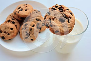 Glass of milk and chocolate chip cookies on white background. View from above. Close-up. Copy space