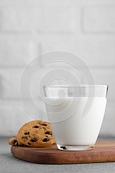 glass of milk and chocolate chip cookies with white brick wall as background