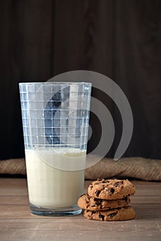 A glass of milk and cookies with chocolate chips.