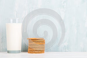 A glass of milk and cookies on the table, on a blue background, minimalism. Copy space