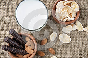 A glass of milk with cookies on a wooden board on a background sacking, burlap