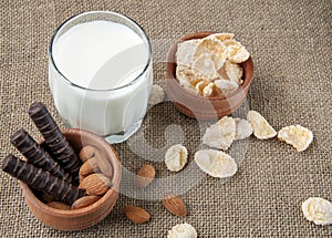 A glass of milk with cookies on a wooden board on a background sacking, burlap
