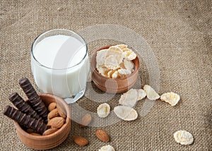 A glass of milk with cookies on a wooden board on a background sacking, burlap