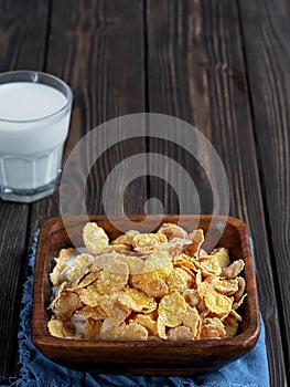 Glass of milk , corn cereals in a wooden plate on dark wooden table. Close up, copy space for text. Shallow depth of field