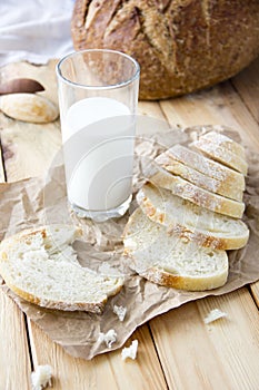 a glass of milk and cut bread on a wooden table and scattered