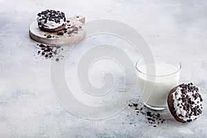 Glass of milk and doughnuts with black cookies on stone kitchen table background. Space for text