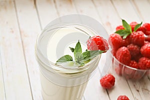 A glass of milk and fresh raspberries with mint on a white background, close-up. Healthy, proper nutrition. Diet. Fruits