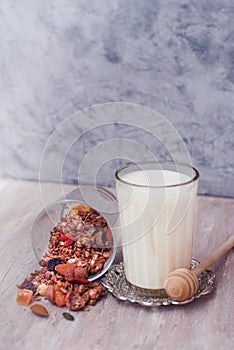 Glass of Milk and Granola bowl. Healthy Nuts and Dried Fruits on Rustic Wooden Background. Wooden Honney Spoon. Top view.