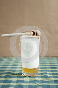 A glass of milk with honey and wooden spoon