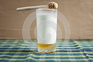 A glass of milk with honey and wooden spoon