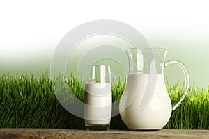 Glass of milk and jar on meadow