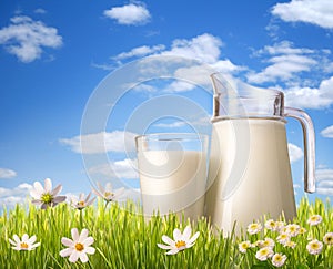 Glass of milk and jug in grass