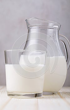 Glass of milk with a jug on a wooden table