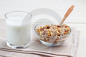 A glass of milk and muesli in glassware and a wooden spoon