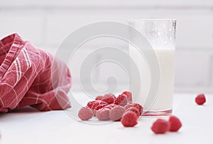 Glass of milk and ripe raspberries. White background