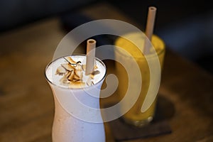 A glass of milk shake and mango smoothie with wooden straw for environmet friendly