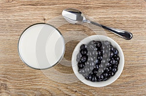 Glass of milk, spoon and bowl with blueberries on table