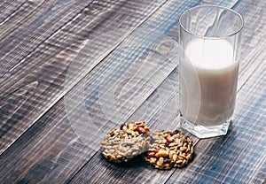 Glass of milk with two cookies on wooden table