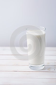 Glass of milk on white rustic wooden background photo