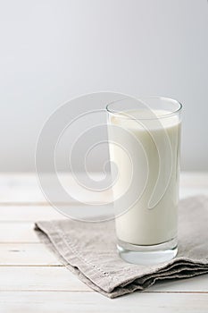 Glass of milk on white rustic wooden background photo