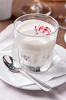 Glass of milkshake with berry syrup close-up on table