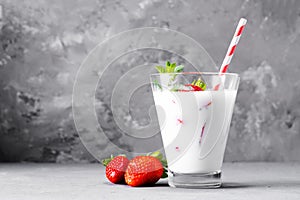 Glass of milkshake with strawberries and mint on a concrete surface. Kefir cocktail with strawberries and banana. close-up.