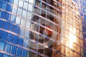 Glass mirror skyscraper wall with blue sky and red sunlight reflection close up, modern business center view