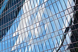 Glass mirror skyscraper wall with blue sky and white clouds reflection close up, modern business center view