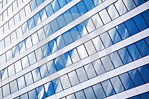 Glass mirror skyscraper wall with blue sky and white clouds reflection close up, modern business center view