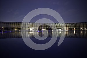 Glass modern building at night lighted across calm lake, tube shape, manila