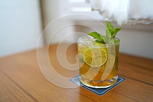 A glass of Mojito cocktail - Made with lime, mint, cane sugar and soda on blurred background and with copy space, A popular summer