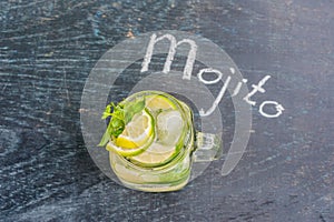 Glass of mojito with lime and mint ice cube close-up on dark wood background