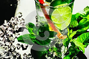 Glass of mojito with lime and mint ice cube close-up red straw