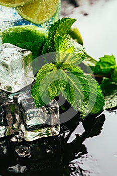 Glass of mojito with lime and mint ice cube close-up red straw on dark background