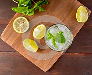 Glass with mojitos and lemon wedges and mint on a tray
