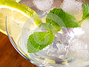 Glass with mojitos and lemon wedges and mint on a tray