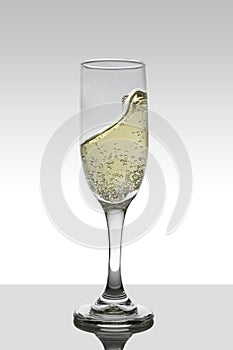glass with moving white wine and white gradient color background with coffee.